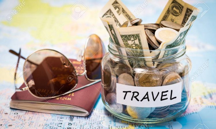 Travel budget concept. Travel money savings in a glass jar with passport and sunglasses on world map